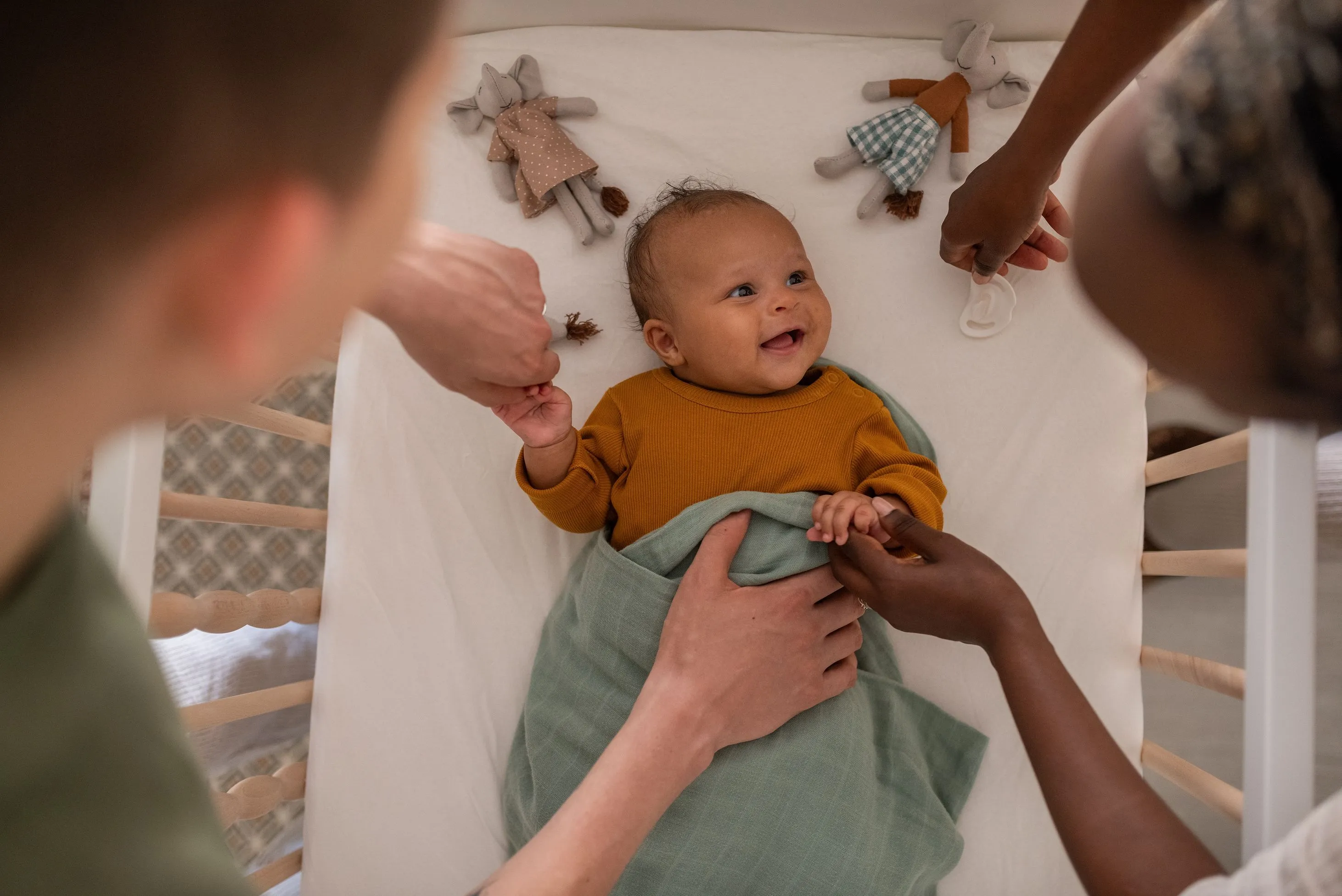 Baby smiling at parents while resting in crib
